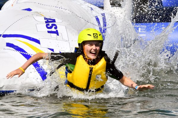 Woman smiling as she splashed into the water off an inflatable