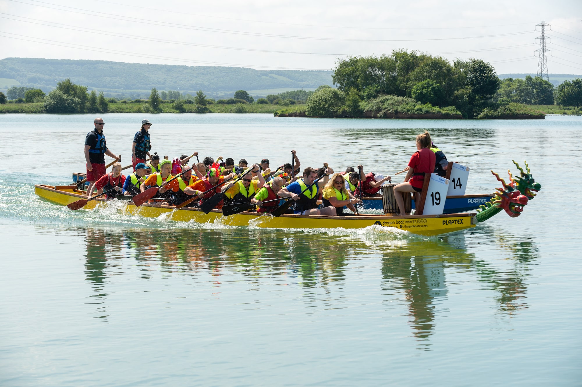 Two dragon boats filled with people rowing, neck and neck in the race