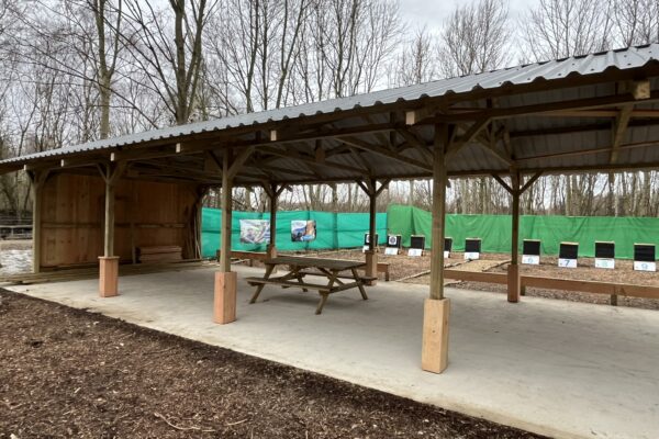 An outdoor activity area for archery featuring a row of targets surrounded by woodland