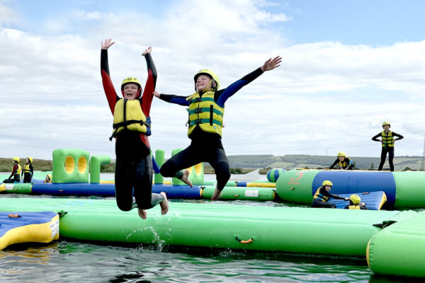 Two people leaping in the air happily while taking part in water sports activities at North Yorkshire Water Park
