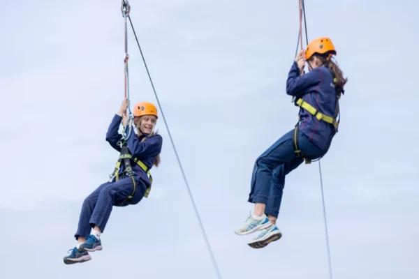 Two smiling people suspended in air taking part in the North Yorkshire Water Park Zipline activity