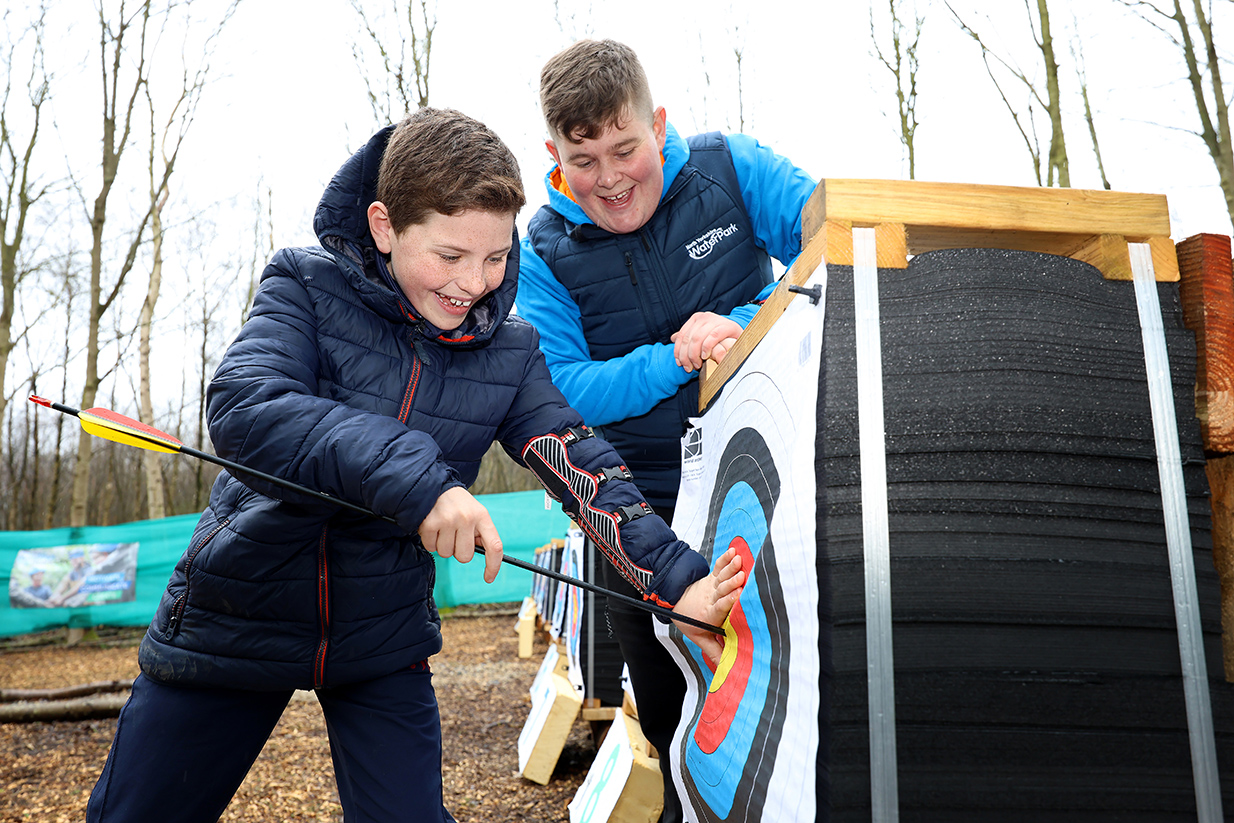 A young person removes an arrow at a brightly coloured target in a woodland in North Yorkshire