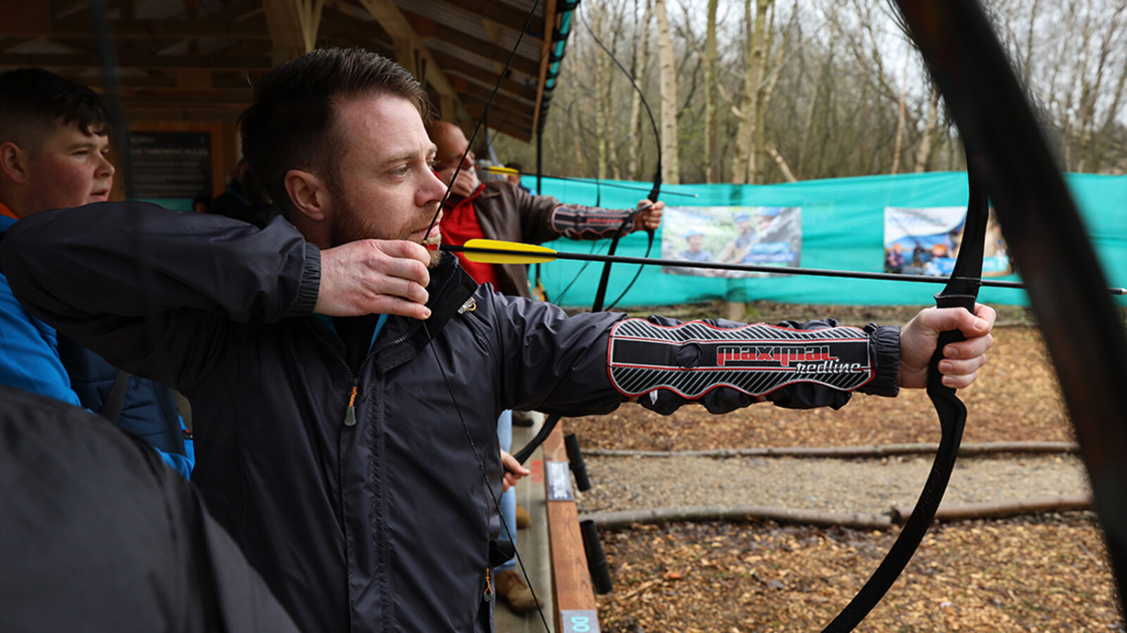 Man takes aim with a bow and arrow in adventure wood, north yorkshire water park.
