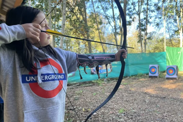 A young person prepares to fire an arrow at a brightly coloured target in a woodland in North Yorkshire