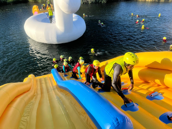 People climbing up large inflatable unicorn with small unicorn in background