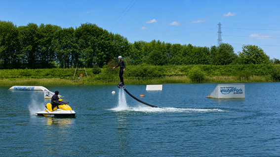 Flyboarding and jetski on lake at north yorkshire water park with big kicker ramp in the background
