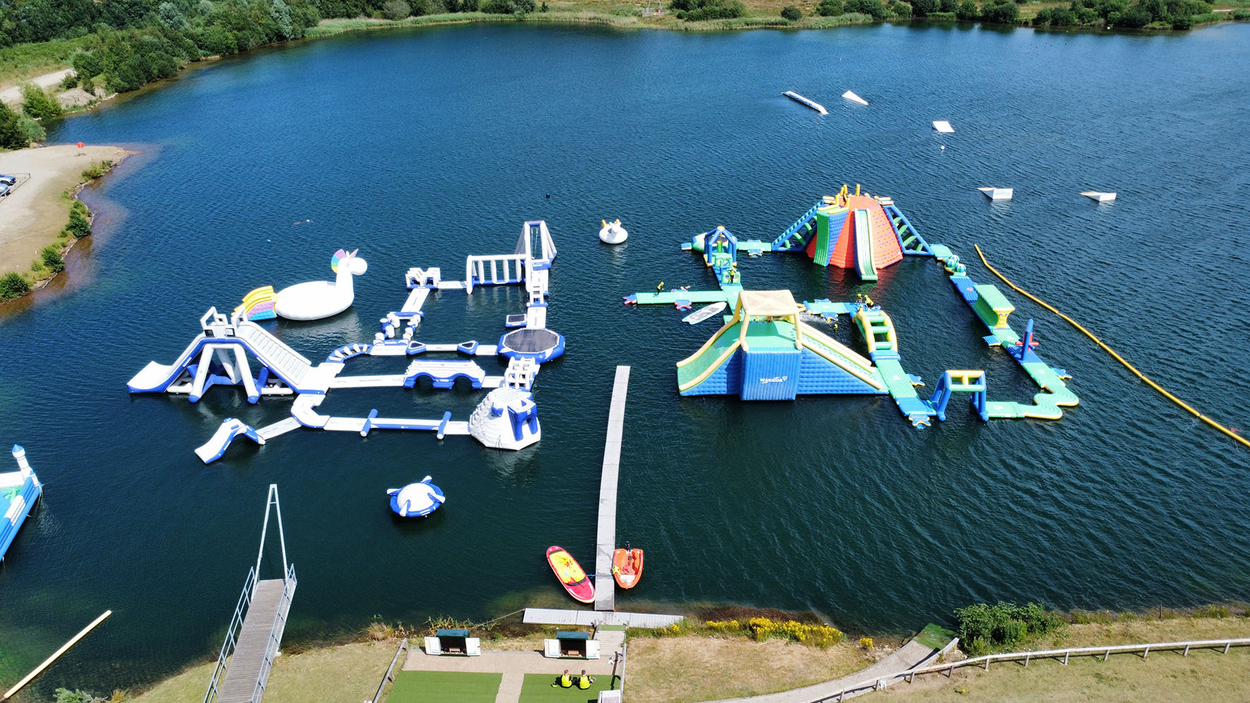 The ultimate inflatable aquaparks on a lake with cafe and reception buildings in background.